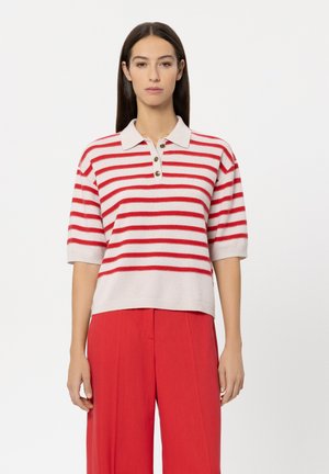 Knit polo sweater with short sleeves, featuring red and white stripes, a collar, and button closure. Paired with wide-leg red trousers.