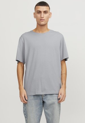 T-shirt à manches courtes gris clair en tissu doux avec un fit décontracté et un col rond, associé à un jean bleu délavé.