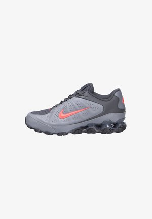 Sneaker atletica grigia con swoosh Nike corallo, tomaia in mesh, suola ammortizzata e ammortizzazione air-sole nera, mostrata di profilo.