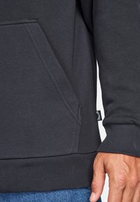 Dark gray sweatshirt showcasing a kangaroo pocket, ribbed cuffs, and hem. Soft texture with subtle detailing and a logo tag on the side.
