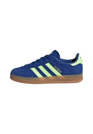 Blå Adidas Gazelle ruskindssneaker med lysegrønne striber, gummisål og "Gazelle" mærket på siden.