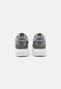 Sive tenisice s teksturiranim materijalom i glatkim naglascima, s bijelim đonom i "Karl Lagerfeld" brendom na peti.