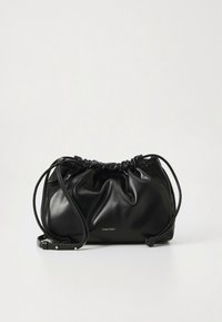 Musta nahkainen käsilaukku, jossa on kiristetty yläosa, säädettävä hihna ja hillitty logo. Sileä pinta ja pehmeä, pyöreä muoto.