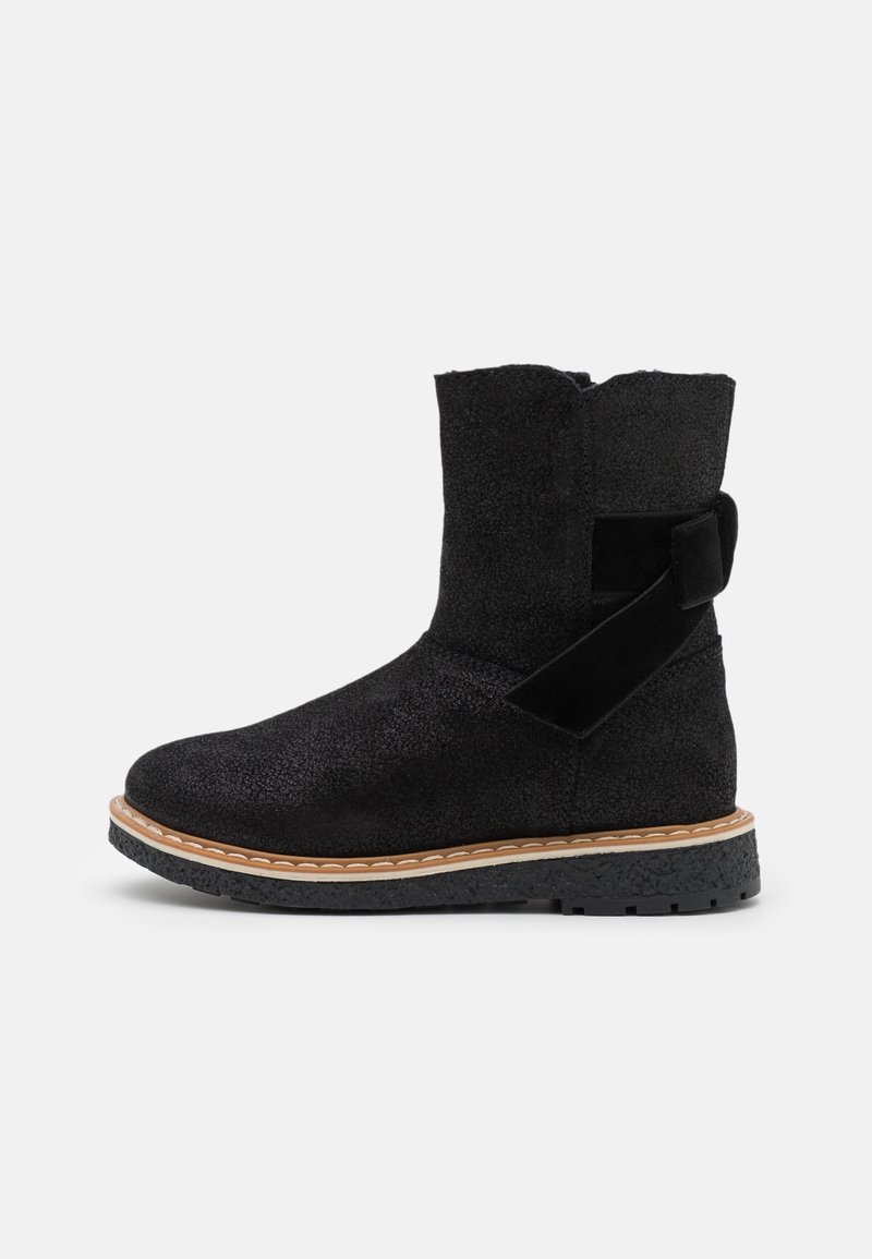 Botte mi-mollet en daim noir avec semelle en caoutchouc, détails de couture couleur fauve, bride latérale décorative et nœud sur fond uni.