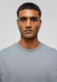 Lichtgrijs katoenen t-shirt met een klassiek ronde halsontwerp, korte mouwen en een gladde textuur. Eenvoudige en minimalistische stijl.