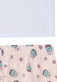 Maglietta bianca in cotone sopra pantaloni da pigiama rosa con un motivo di cactus, cuori e fiori, vita elastica e morbidezza al tatto.