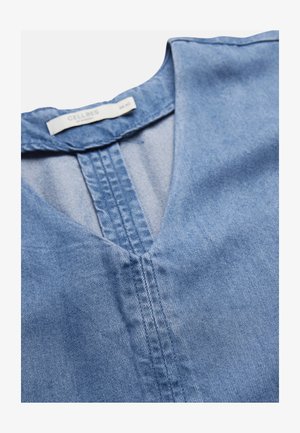 Lichtblauw denim shirt met V-hals en zichtbare verticale stiksels langs de halslijn en het label in de kraag met de tekst "Cellbes".