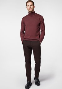 Burgundzki golf z dopasowanym krojem, w połączeniu z ciemnobrązowymi spodniami slim-fit i czarnymi botkami za kostkę z grubą podeszwą.