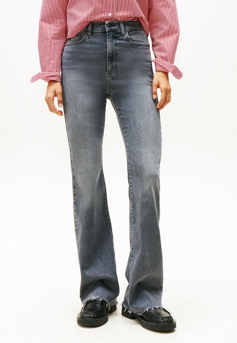 Jeans a vita alta in denim grigio sbiadito, con taglio dritto e orlo sfrangiato. Abbinati a mocassini neri per un contrasto.