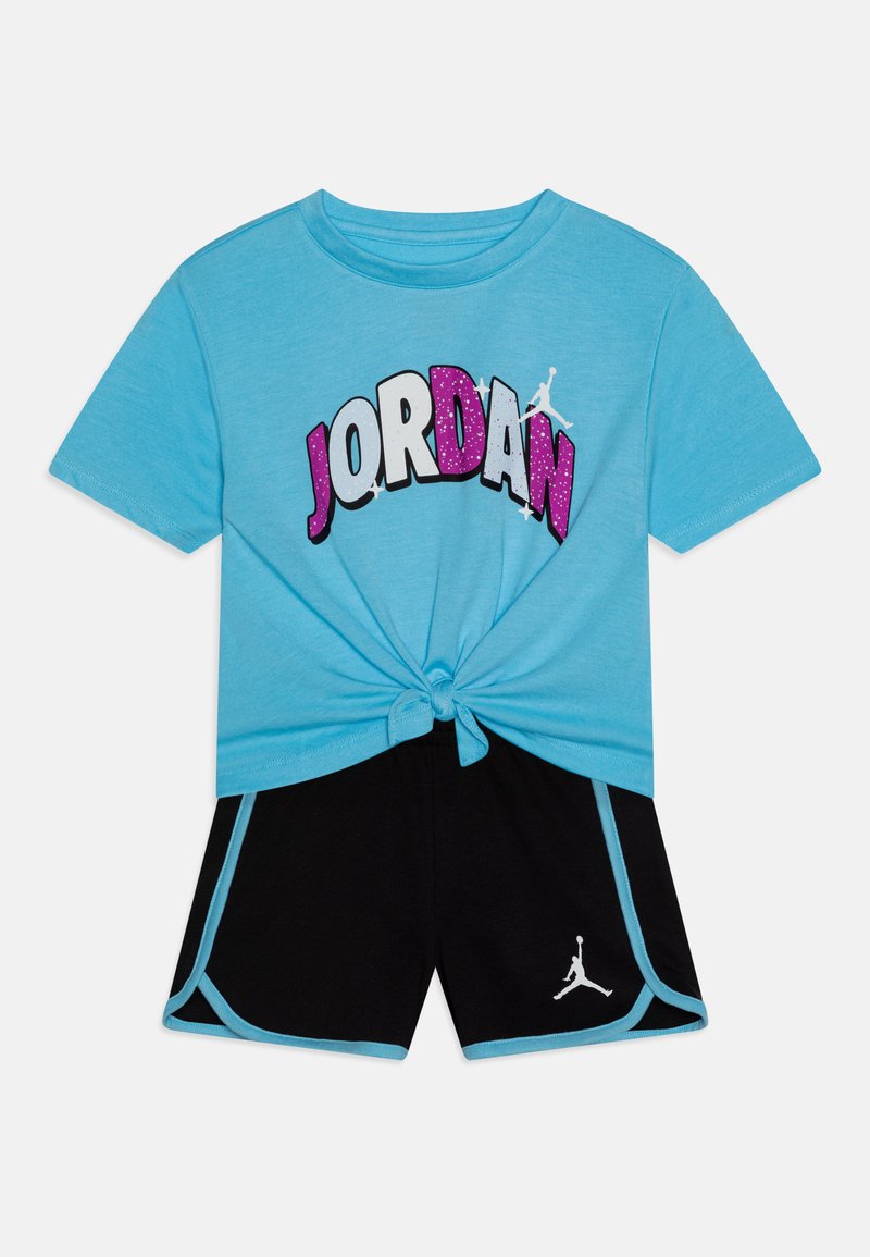 Maglietta a maniche corte blu con grafica 'JORDAN' e pantaloni corti neri con logo bianco e rifiniture azzurre chiare sui bordi. Dettaglio nodo all'orlo della maglietta.
