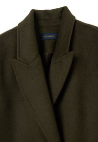 Abrigo de mezcla de lana color verde oliva con cuello con muesca, hombros estructurados y forro interior suave. La etiqueta dice "PIOMBO".