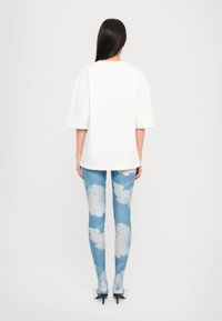 Hvit oversized t-skjorte med korte ermer, sammen med lyseblå leggings med sky-mønster. Svart hæler fullfører antrekket.