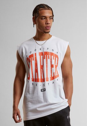 White sleeveless t-shirt featuring bold red "STARTER" text, distressed pattern, and a round neckline, paired with dark shorts.