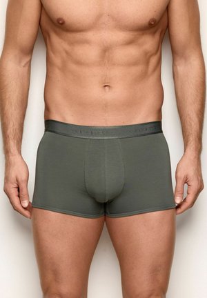 Męskie bokserki w oliwkowej zieleni z miękkim paskiem w pasie ozdobionym wytłoczonym nazwą marki. Materiał wydaje się gładki i dopasowany, z średnim stanem.