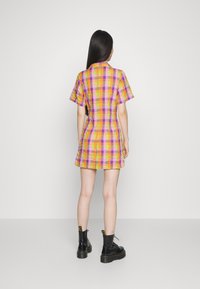 Vestido de manga curta em padrões xadrez em tons de amarelo, rosa e roxo; forma ajustada com saia rodada; tecido texturizado; apresenta bolsos laterais.