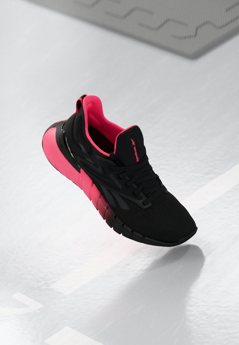 Adidas sportivă neagră cu accente roz, superior din plasă respirabilă, guler căptușit și talpă texturată pentru aderență și flexibilitate.