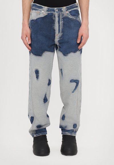Modré a šedé patchwork džíny vyrobené z denimu s poškozenými vzory, volným střihem, kovovým knoflíkem na zapínání a kontrastním prošíváním.