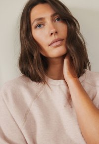 Lichtroze geribde sweatshirt met een ronde hals en raglanmouwen, textuurstof, voorzien van subtiele stikdetails.