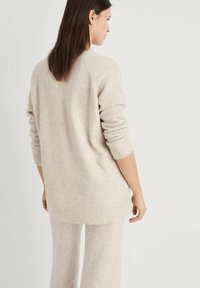 Beiger Pullover aus weichem Material, mit gerippten Bündchen und Saum, überschnittenen Schultern und einem lässigen Schnitt, kombiniert mit passenden Hosen.