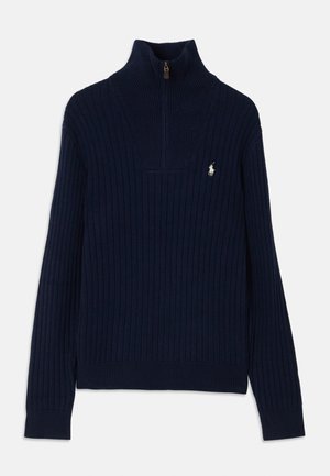 Suéter de punto acanalado azul marino con cuello alto y medio zip. Presenta un pequeño logo en el lado izquierdo del pecho. Textura suave y diseño ajustado.