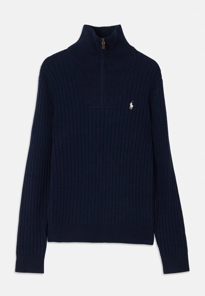 Suéter de punto acanalado azul marino con cuello alto y medio zip. Presenta un pequeño logo en el lado izquierdo del pecho. Textura suave y diseño ajustado.
