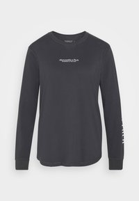 Langærmet sort bomulds T-shirt med rund hals, der har hvid tekstlogo på bryst og ærme. Enkel design, ingen mønstre eller detaljer.