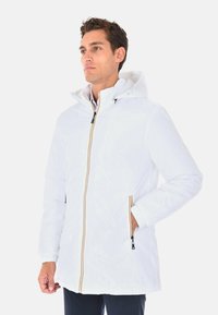 Giacca impermeabile bianca con cappuccio, zip gialla in evidenza e tasche laterali. Realizzata in materiale leggero, con maniche lunghe e polsini elastici.