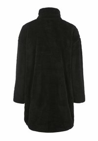 Schwarze, flauschige Fleece-Oberbekleidung hat einen hohen Kragen und weite Ärmel, mit einem lockeren Schnitt und ohne sichtbare Verschlüsse.