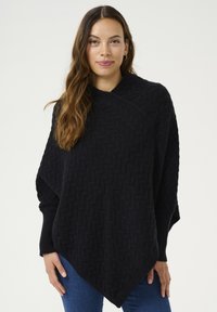 Mustassa neuleponchossa on teksturoitu kalanruotokuvio, jossa on valuvampi muotoilu ja viistot helmat. Pitkät hihat ulottuvat olkapäiltä.
