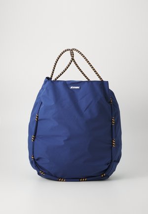 Sac cabas bleu K-Way avec anses en corde noire et jaune et garniture sur un fond clair uni.