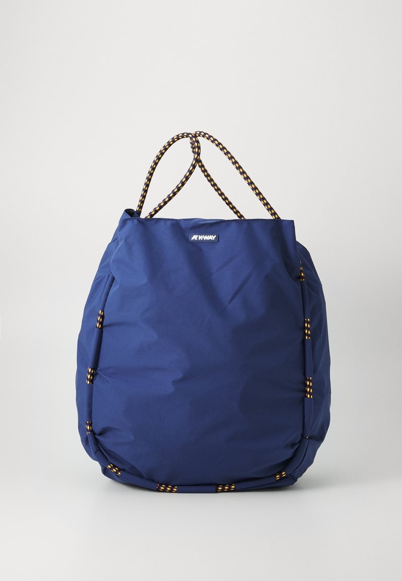 Sac cabas bleu K-Way avec anses en corde noire et jaune et garniture sur un fond clair uni.