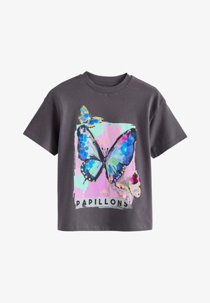 T-shirt gris foncé avec un imprimé papillon coloré sur un fond rose et vert menthe et le mot "PAPILLONS" en dessous.