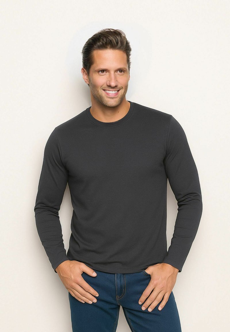 Langärmliges schwarzes Baumwollhemd mit Rundhalsausschnitt, glatter Textur und dezenten Nähten, kombiniert mit blauen Jeans und einem neutralen Hintergrund.