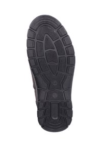 Suela de zapato de goma negra con patrón de agarre texturizado, presenta surcos profundos y un logotipo prominente. Soporta tracción y durabilidad.
