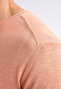 Helles rosa gestricktes Sweatshirt mit weicher Textur. Verfügt über einen runden Halsausschnitt und sichtbare Nähte entlang der Schulternaht.