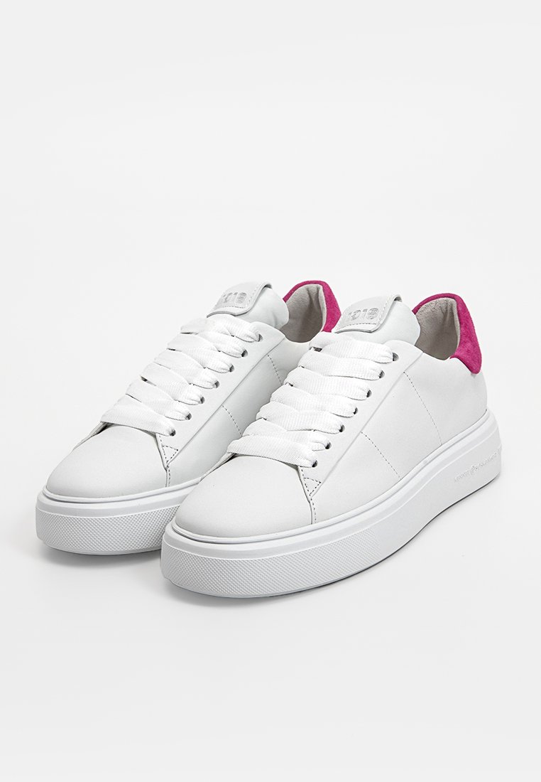 Baskets blanches en cuir avec une semelle de plateforme texturée, ornées d'accents en suède rose au niveau du talon et de lacets blancs. Design minimaliste, sans logos visibles.