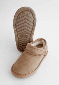 Barna slip-on cipők puha, texturált felsőrésszel és plüss béléssel. Gumi talp, mintás járófelülettel a tapadás és a stabilitás érdekében.