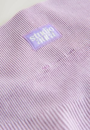 Jasnofioletowa dzianina prążkowana z prostokątną metką, na której białą nicią wyszyto napis "studio aura". Tekstura jest jednolita i gładka.