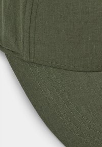Gorra de un verde oscuro con visera redondeada, costuras visibles y tejido texturizado, destacando su material duradero y ligero.