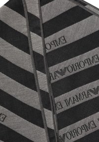 Grå tørklæde med markante sorte diagonale striber og teksten "EMPORIO ARMANI" i et gentaget mønster sammen med et logovalg.