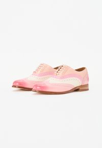 Scarpe wingtip in pelle degradè rosa e crema; presentano dettagli brogue, punta arrotondata e chiusura con lacci su una suola in legno.