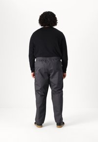 Gray elastic-waist cargo pants with side pockets, paired with a black long-sleeve shirt, viewed from the back. Textured fabric.