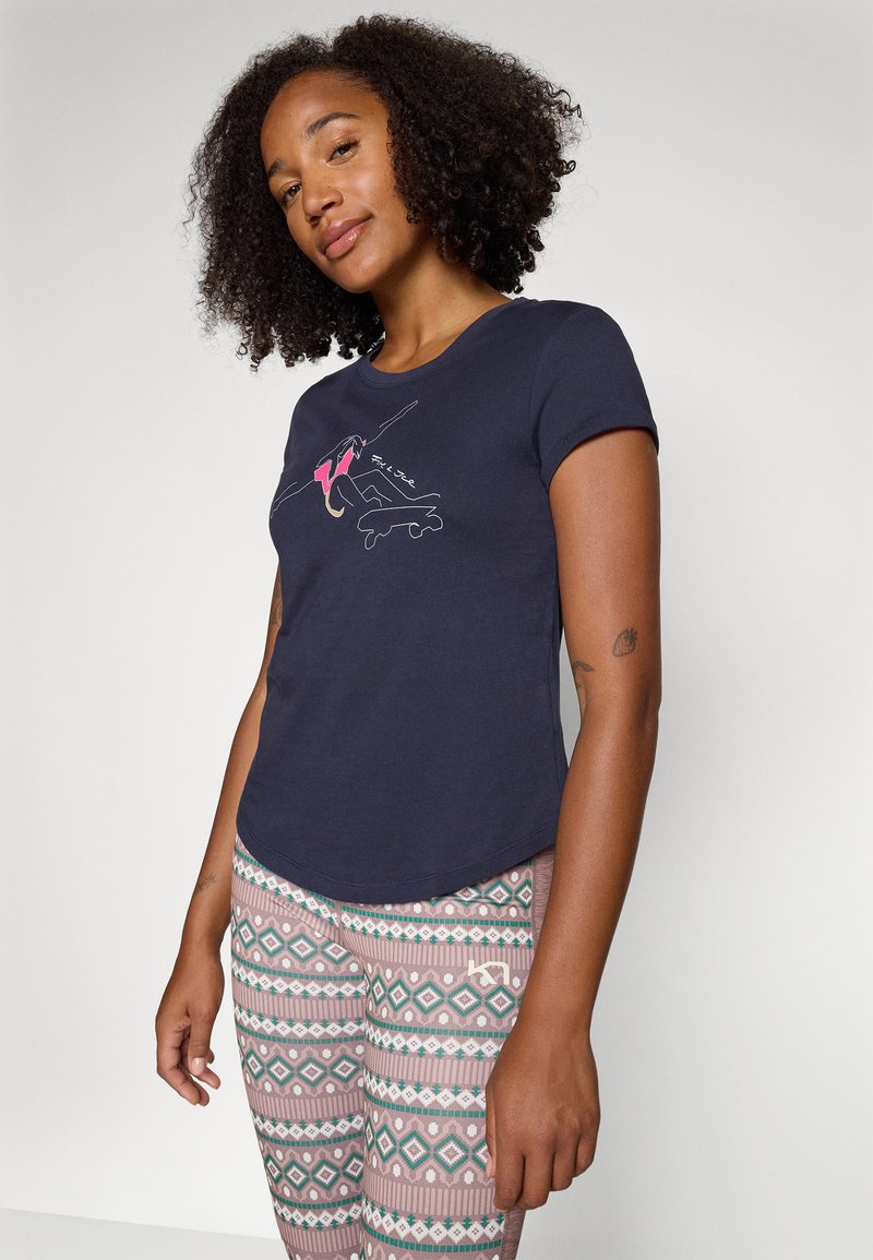 Dunkelblaues T-Shirt mit kurzen Ärmeln und einem grafischen Design, das einen Skateboardfahrer zeigt. Kombiniert mit leggings mit Muster in sanften Pastellfarben.