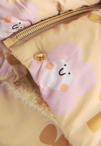 Puffer jacket featuring a yellow fabric with pink flower patterns, golden zipper, and furry lining along the opening for added texture.