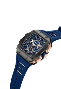 Reloj con correa de goma azul y caja en negro y oro rosa. Presenta una esfera con múltiples diales, acentos azules y marcas plateadas.