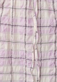 Tessuto a scacchi viola e bianco con linee orizzontali e verticali, caratterizzato da una superficie texturizzata e un design morbido e fluido.