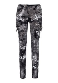 Pantalon cargo noir vieilli avec texte graffiti blanc, accents de poche cloutés et éclaboussures de peinture sur tout le tissu.