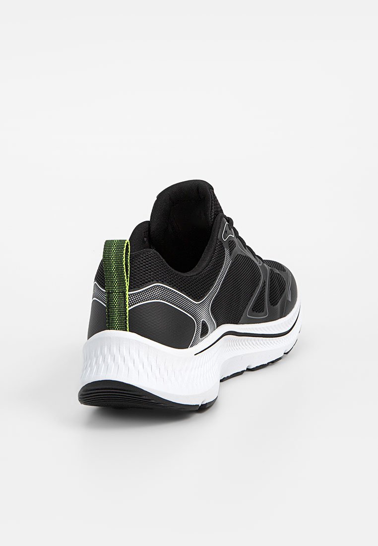 Zapatilla de correr negra con parte superior de malla, mediada blanca y lengüeta verde en el talón. Presenta patrones texturizados y un diseño ligero.