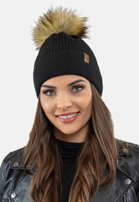 Berretto a maglia nero con un grande pompon in pelliccia sintetica in cima. Presenta un design a coste testurizzate e una piccola etichetta del marchio simile alla pelle.