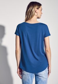 Kungsblå T-shirt i mjukt tyg med korta ärmar, rund halsringning och en något rundad nederkant. Bärs tillsammans med ljusblå jeans.